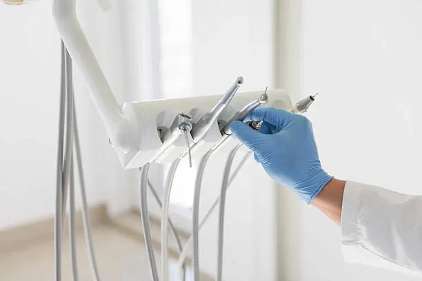 Manos con guantes cogiendo instrumental dental